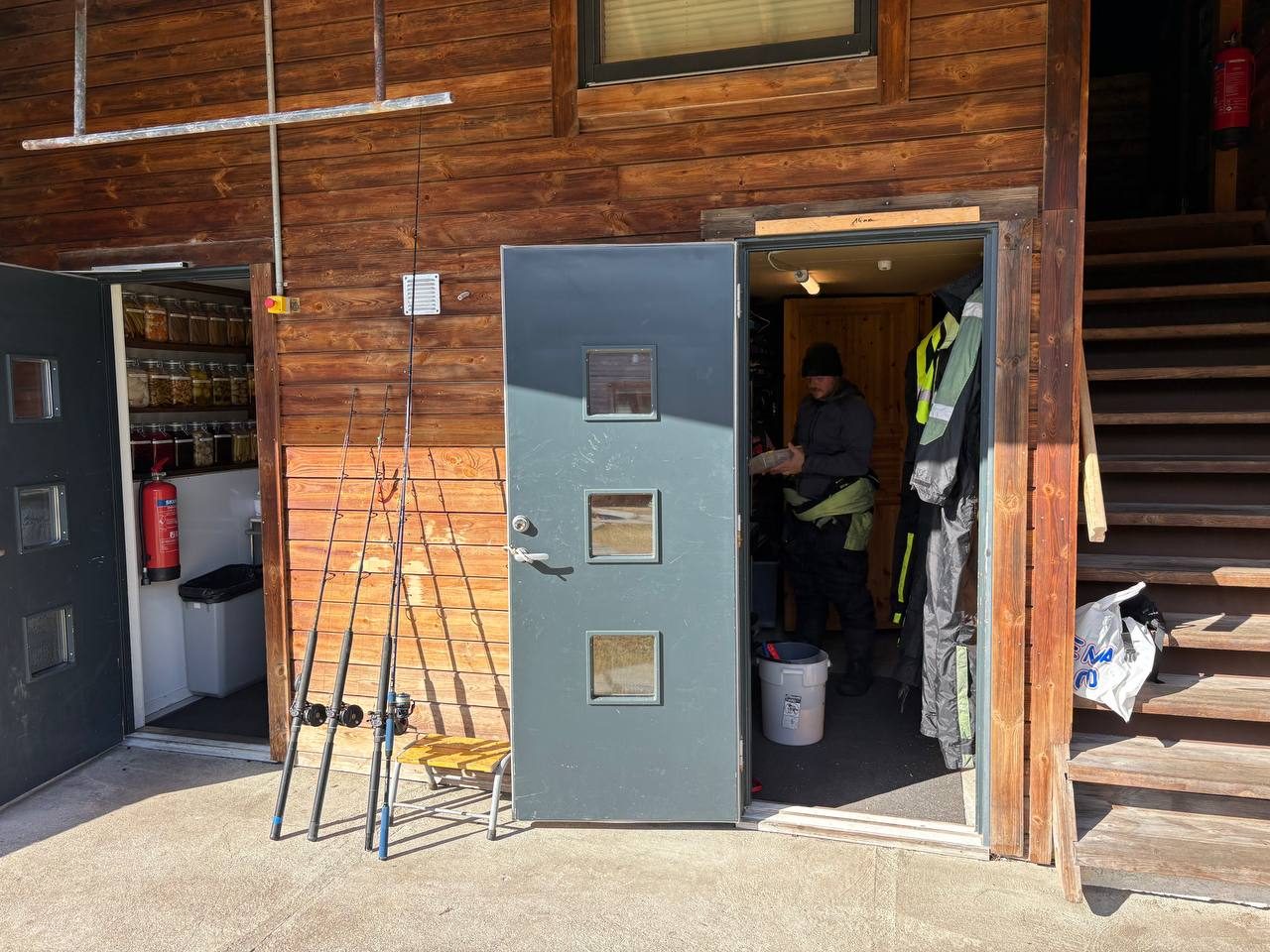 Kůlna s rybářskými pruty a žlutými nepromokavými obleky