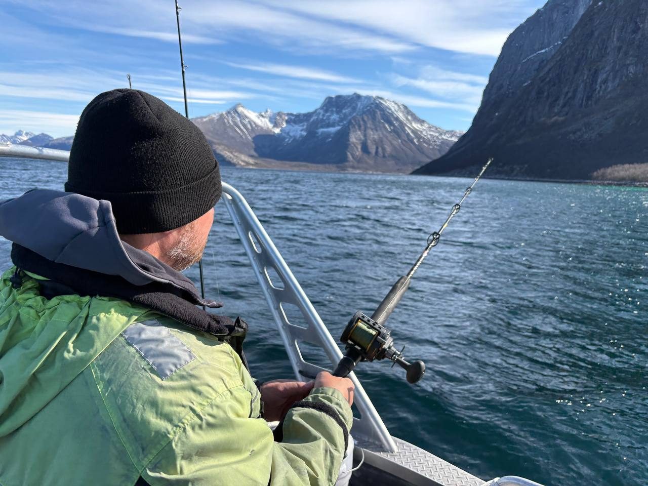 Darek v tmavém rybářském oblečení s prutem na lodi