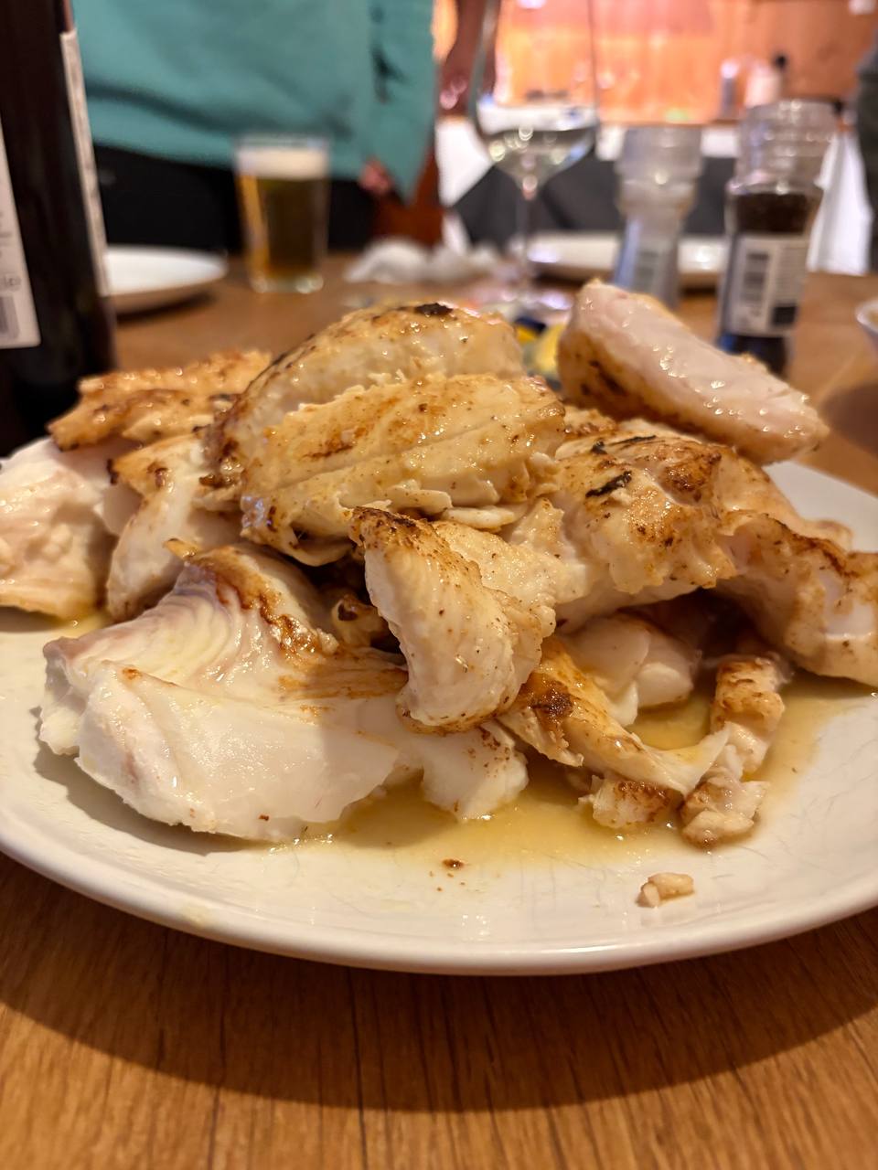 Porce ryby na bílém talíři, zlatavě opečená, s omáčkou