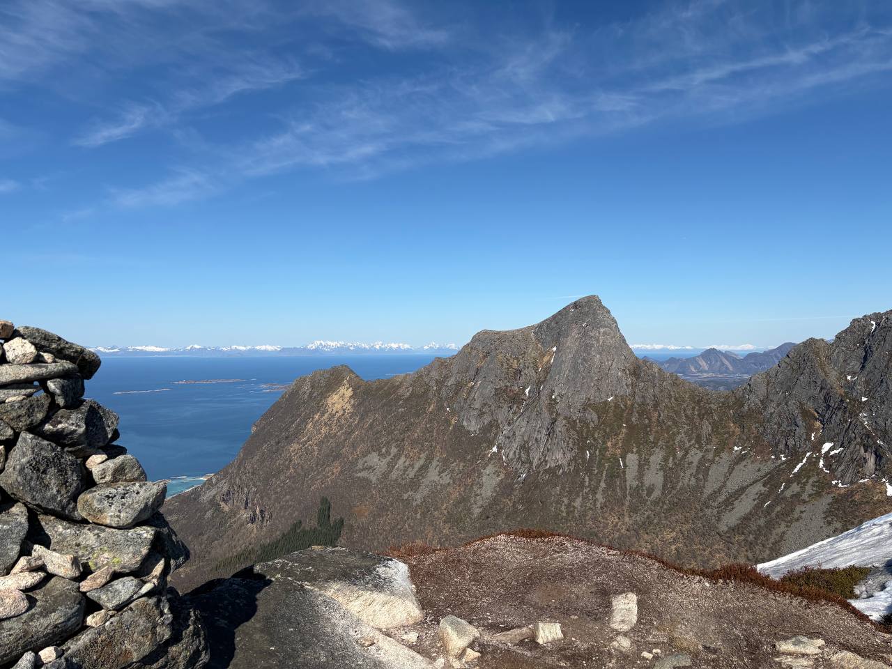Kamenný cairn na skalnatém vrcholu s výhledem na souostroví