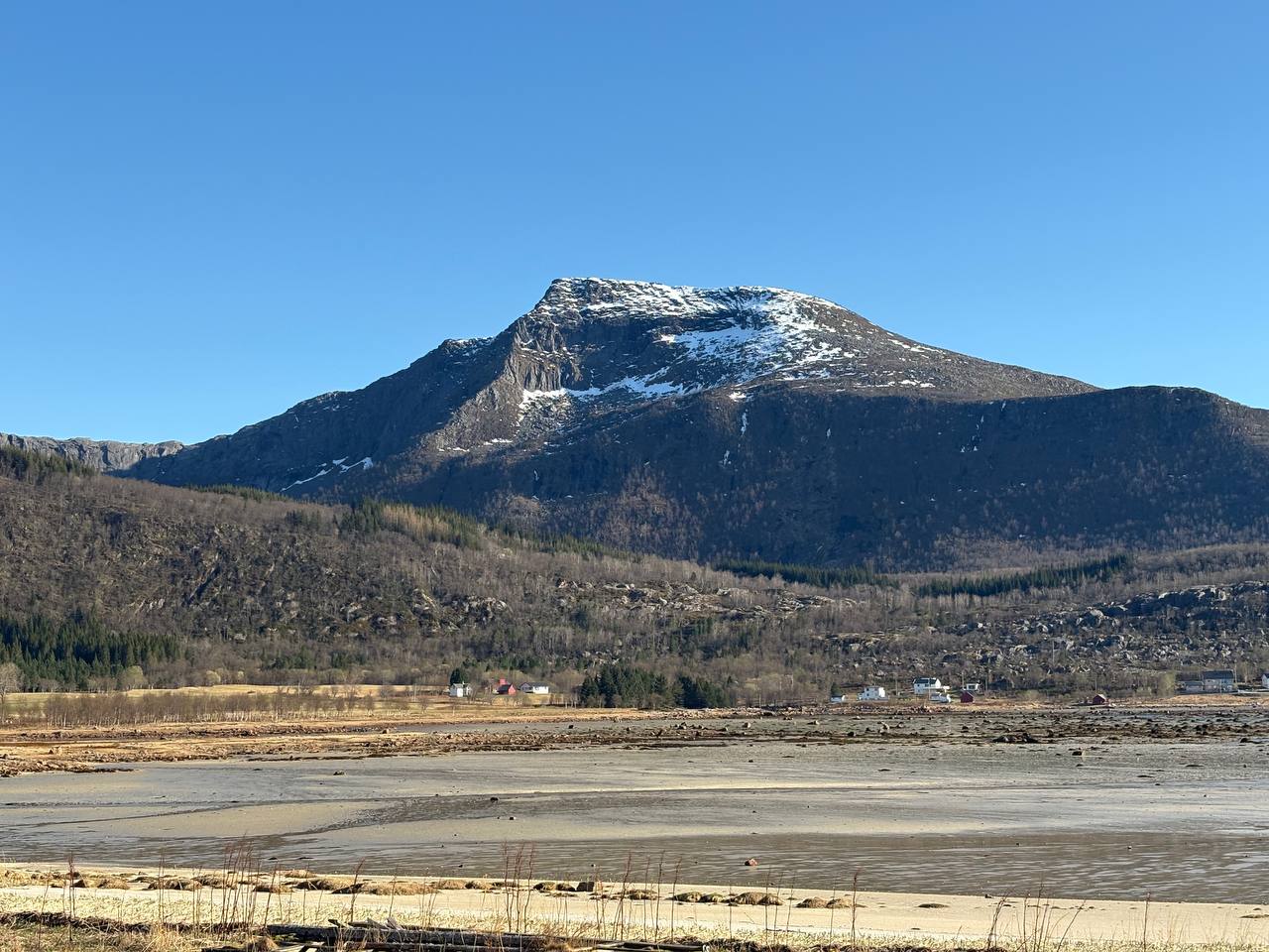 Sørskottinden viděný z pláže, zasněžený vrchol nad fjordem
