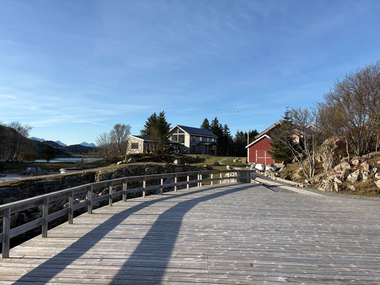 Pohled z mola na klidnou vodu, dřevěný chodník, domy na břehu